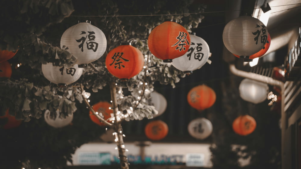 a bunch of orange and white lanterns hanging from a tree