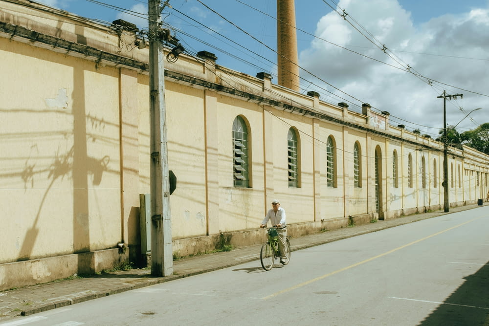 a man riding a bike down a street next to a building