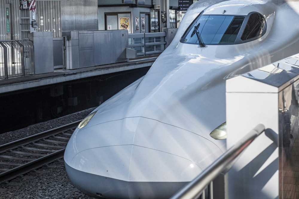 a white bullet train parked at a train station