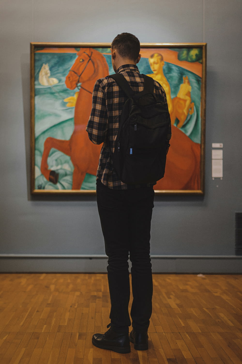 美術館の絵画の前に立つ男性
