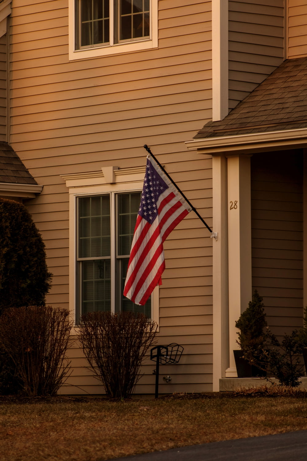 an american flag on a pole in front of a house