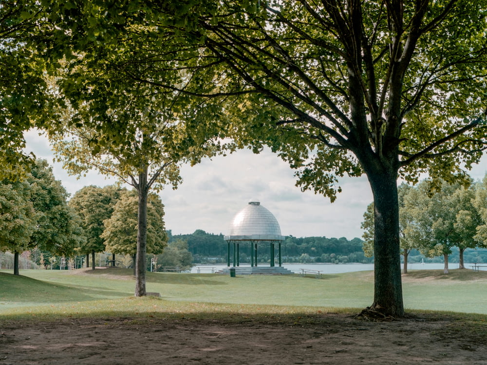 a gazebo in the middle of a park with a lake in the background