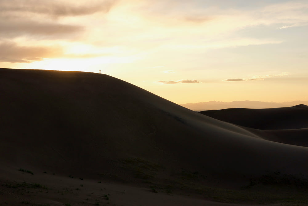 the sun is setting over the sand dunes