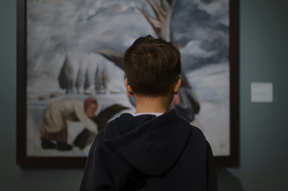 a young boy standing in front of a painting