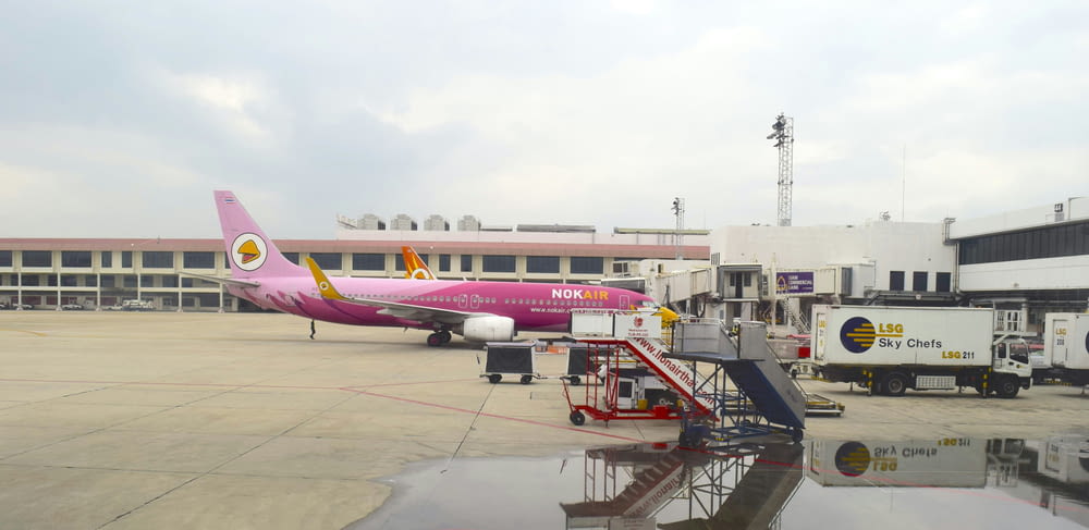 a pink airplane is parked at an airport
