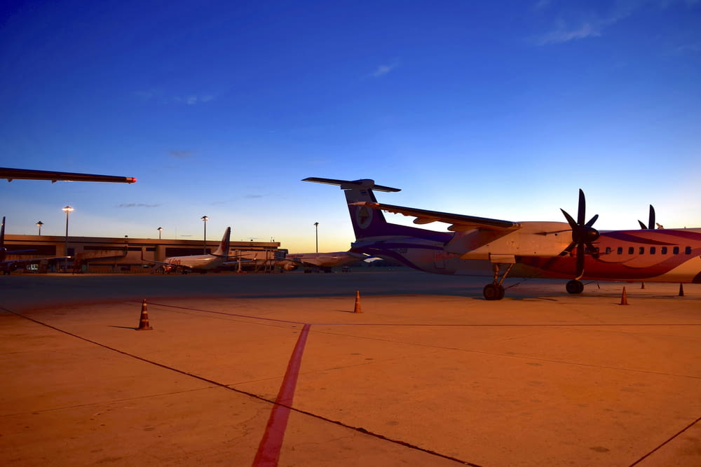 Um avião está estacionado na pista ao pôr do sol