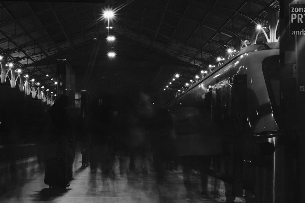 a black and white photo of people in a train station