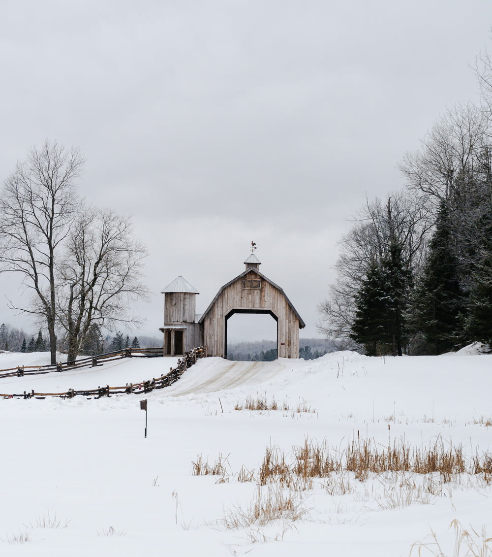 a barn in the middle of a snowy field