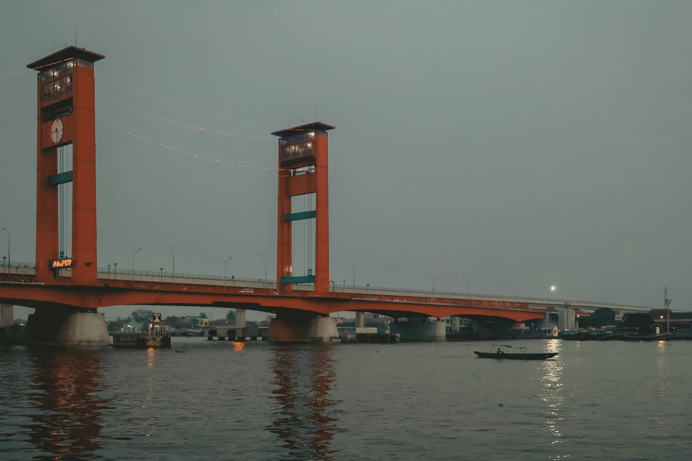 a red bridge with two towers over a body of water