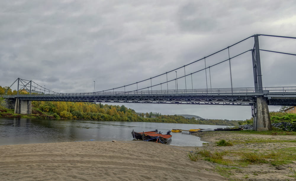 a bridge over a river next to a sandy shore