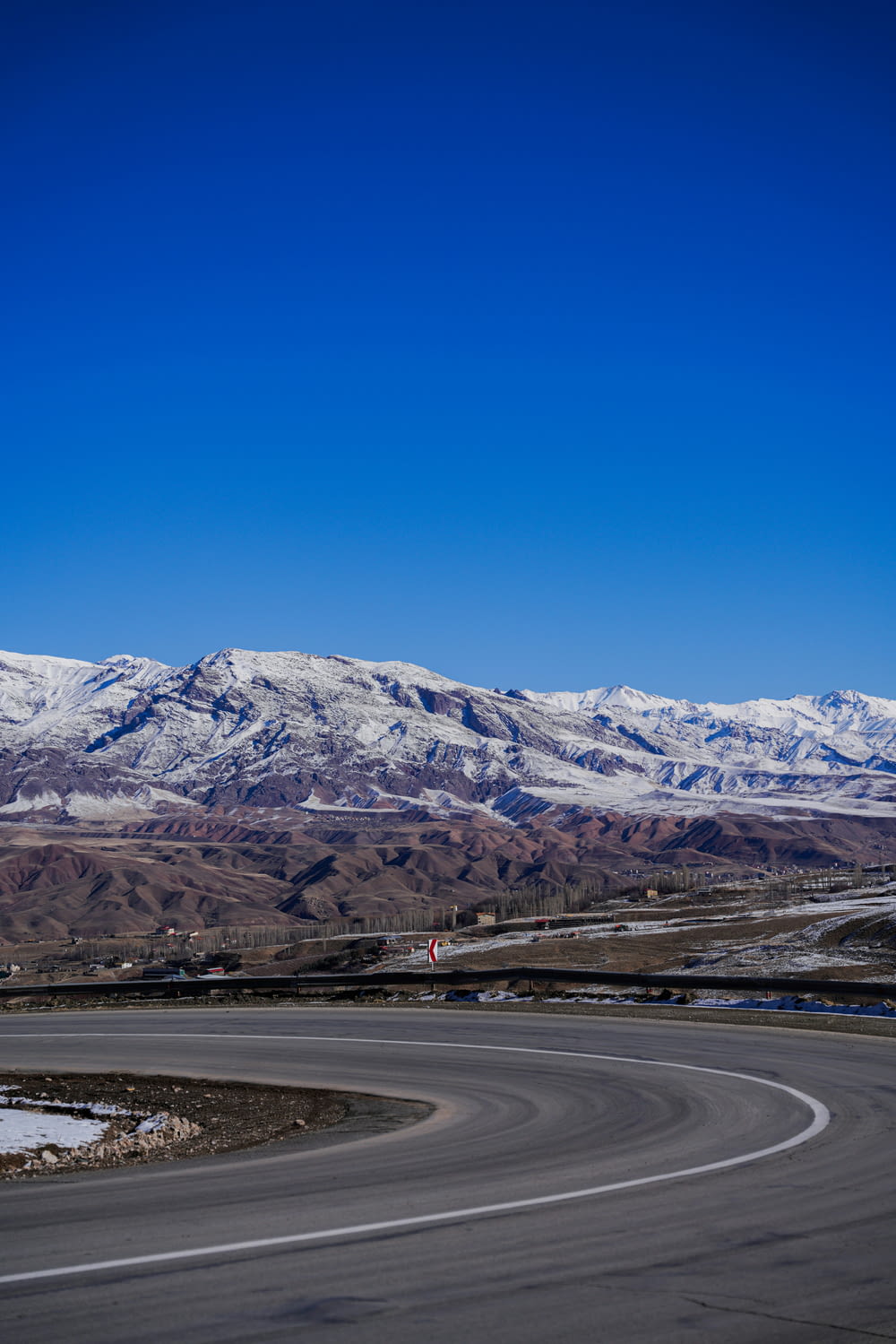 a curved road with snow covered mountains in the background