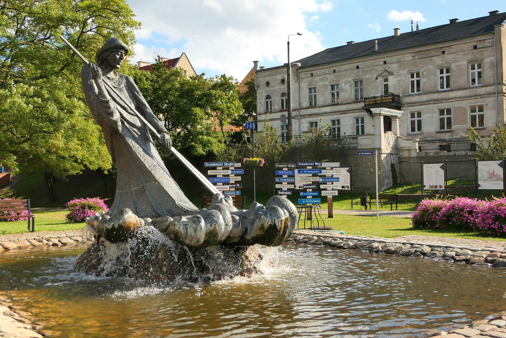 a fountain with a statue of a man holding a staff