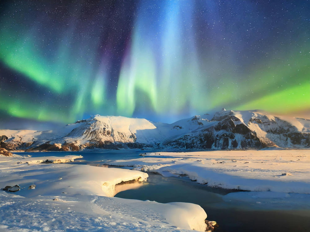 an aurora bore over a snowy mountain range