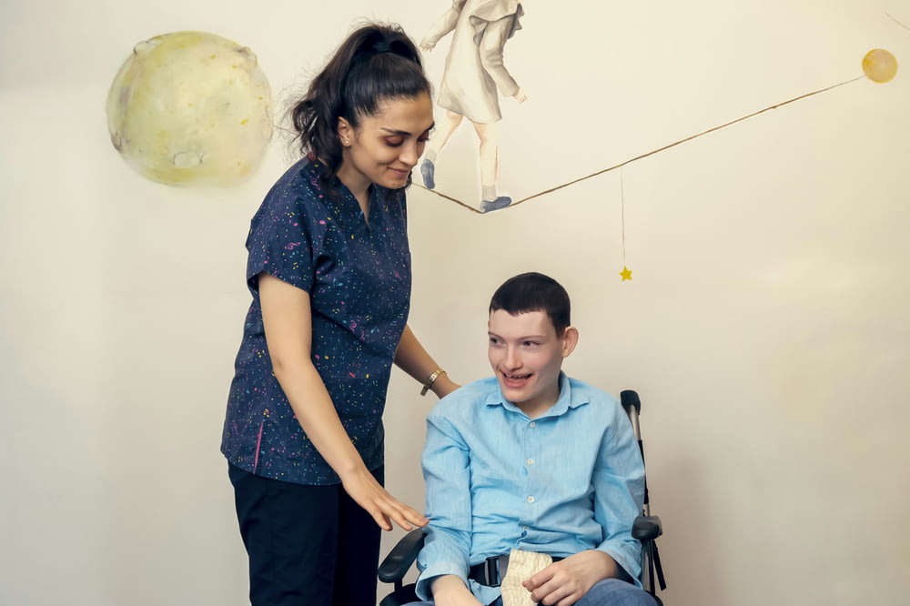 a woman standing next to a man in a wheel chair