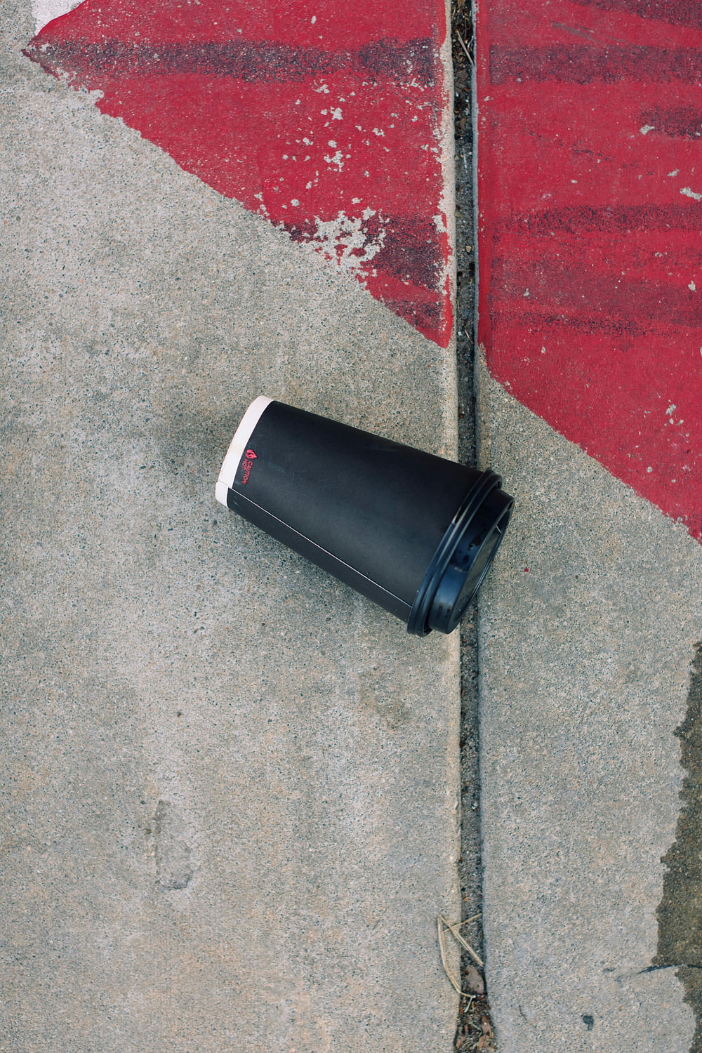 a black trash can sitting on the side of a road