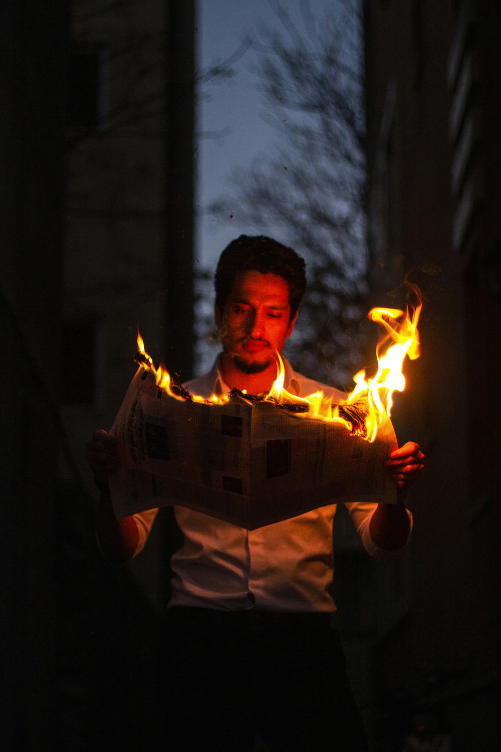 a man holding a newspaper with flames coming out of it