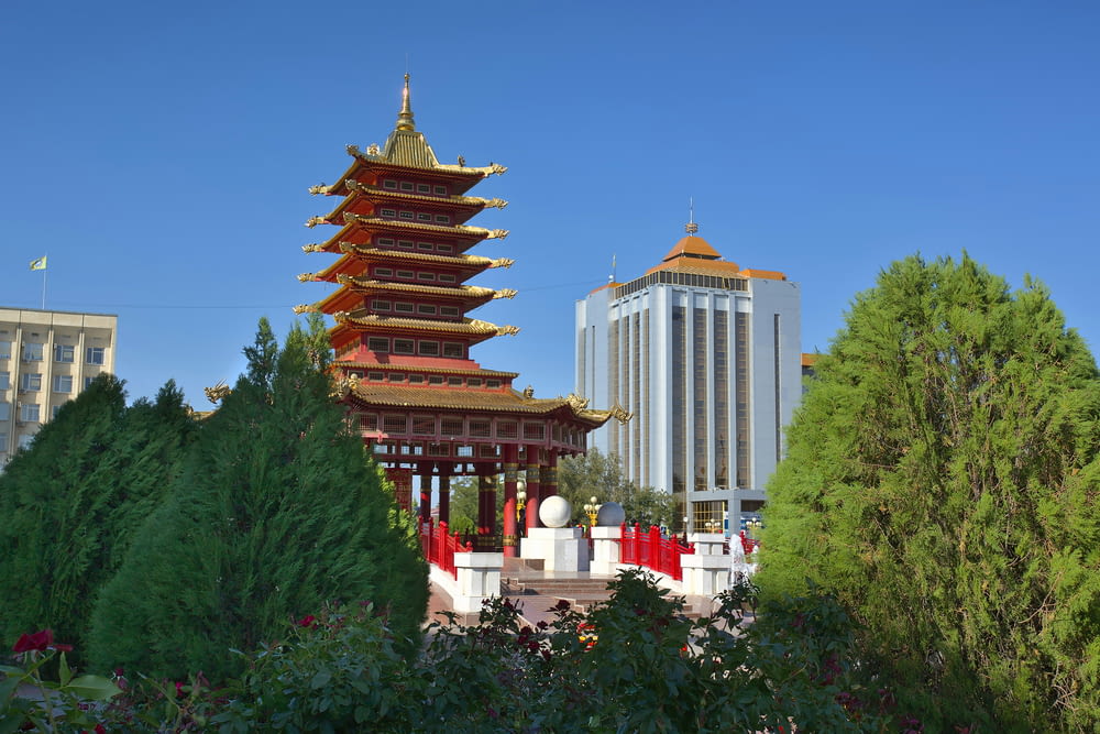 a pagoda in the middle of a park with tall buildings in the background