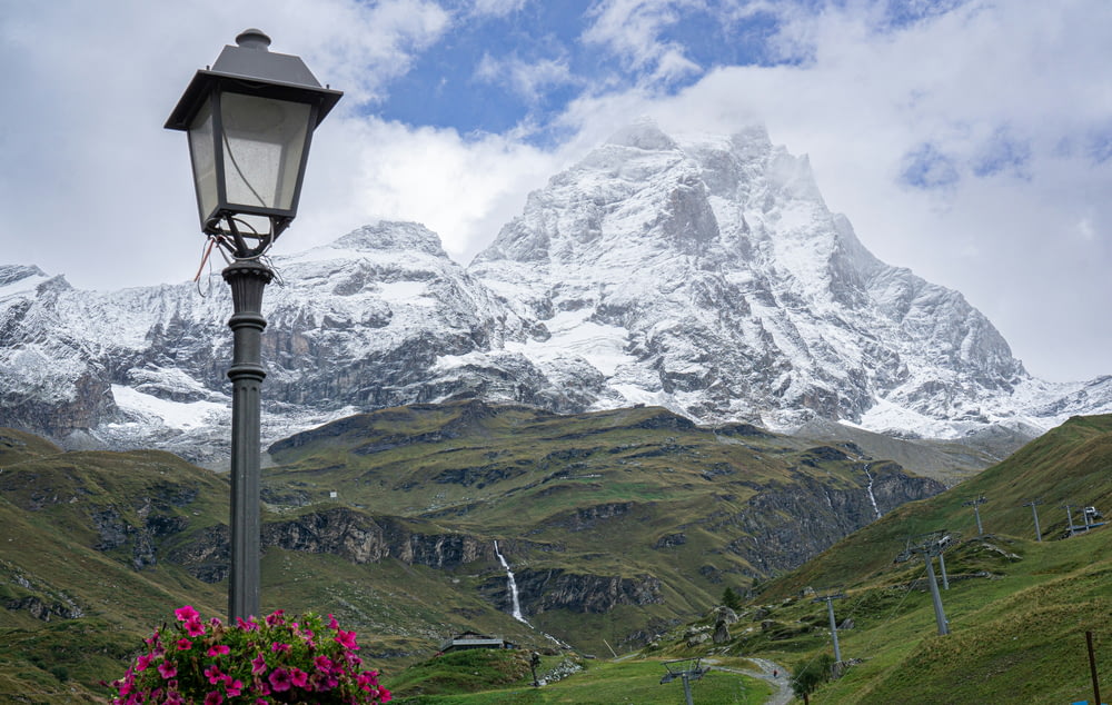 a lamp post in front of a snow covered mountain