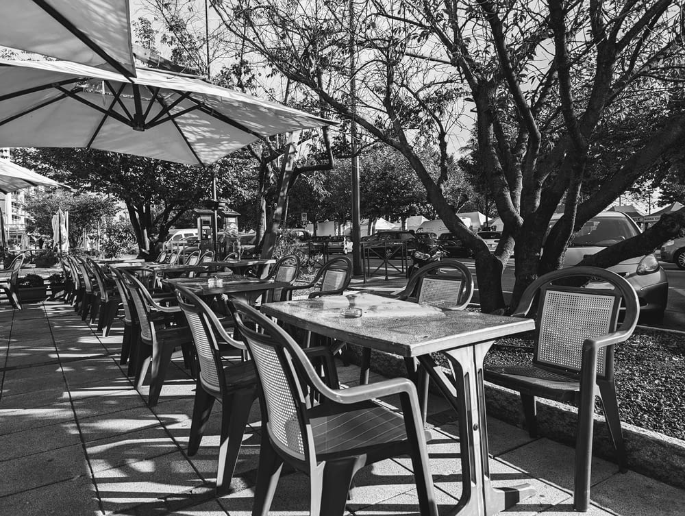 Una foto en blanco y negro de mesas y sillas bajo sombrillas