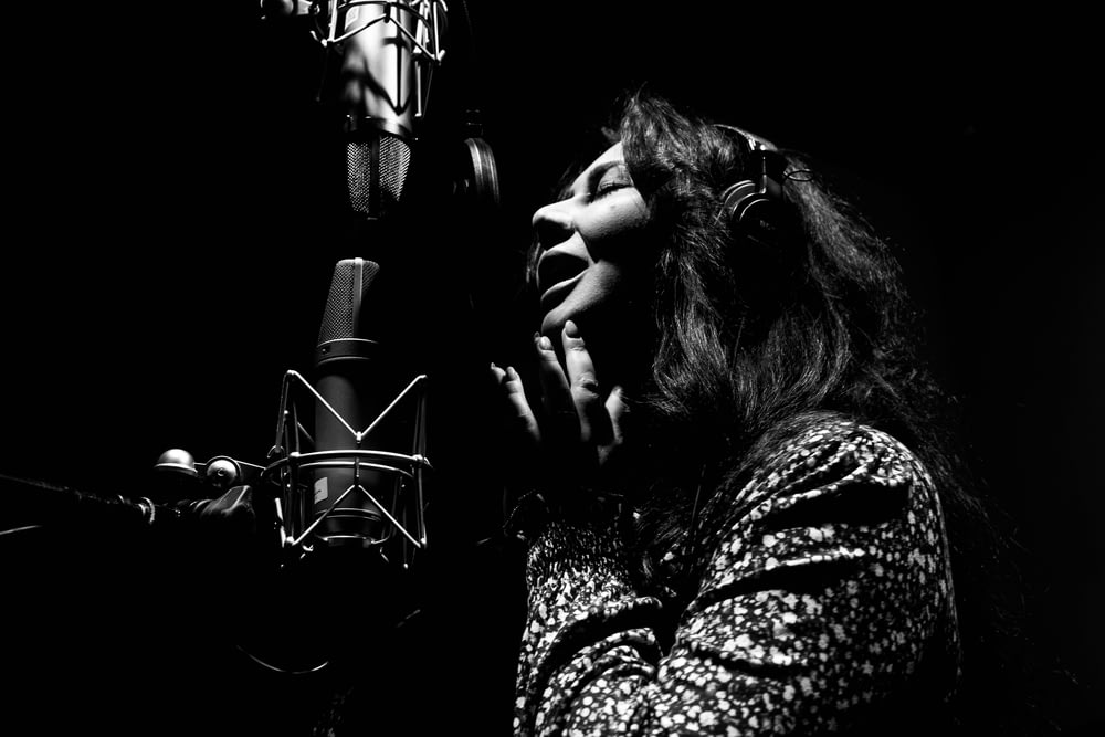 a woman singing into a microphone in front of a microphone