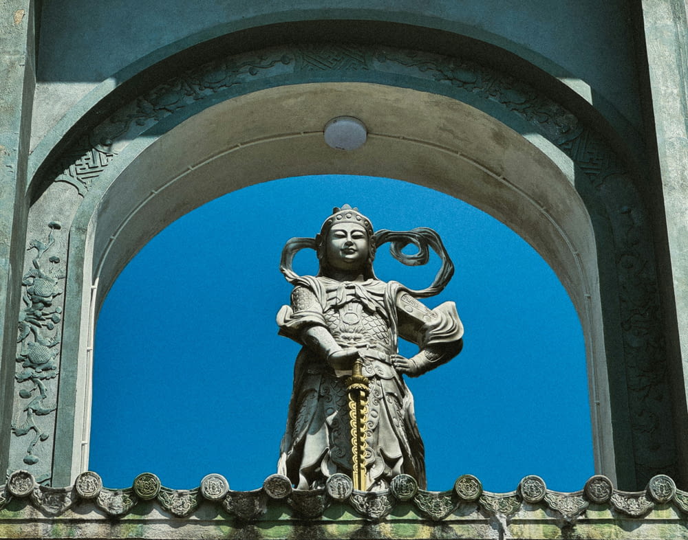 a statue of a person holding a snake on top of a building