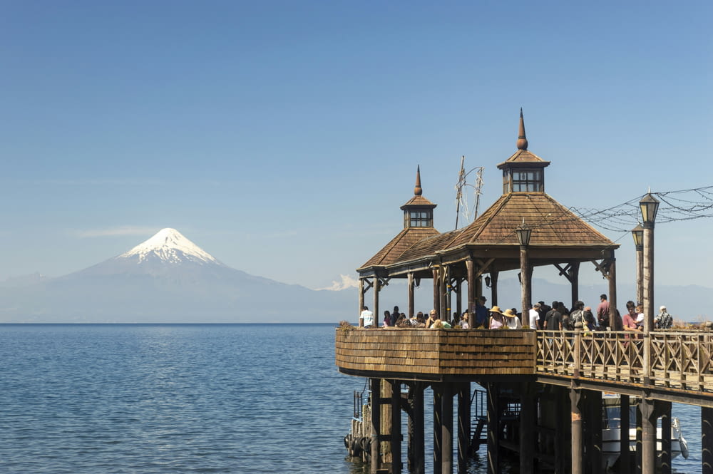 a pier with a gazebo and a mountain in the background