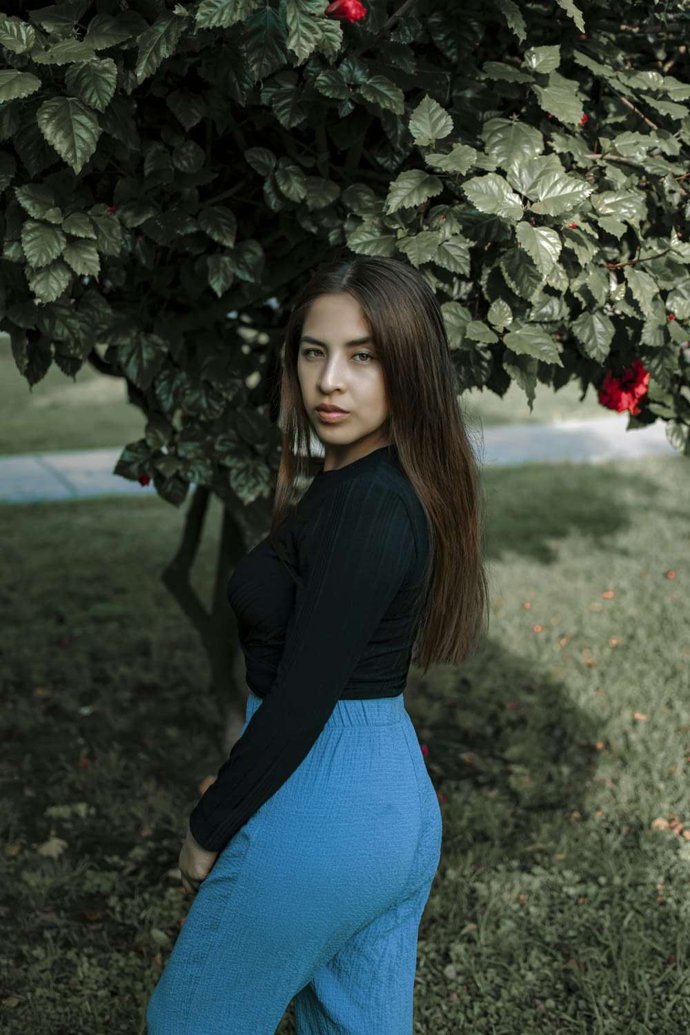 a woman is posing for a picture under a tree