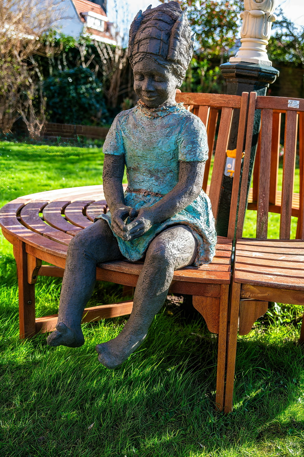 a statue of a girl sitting on a wooden bench