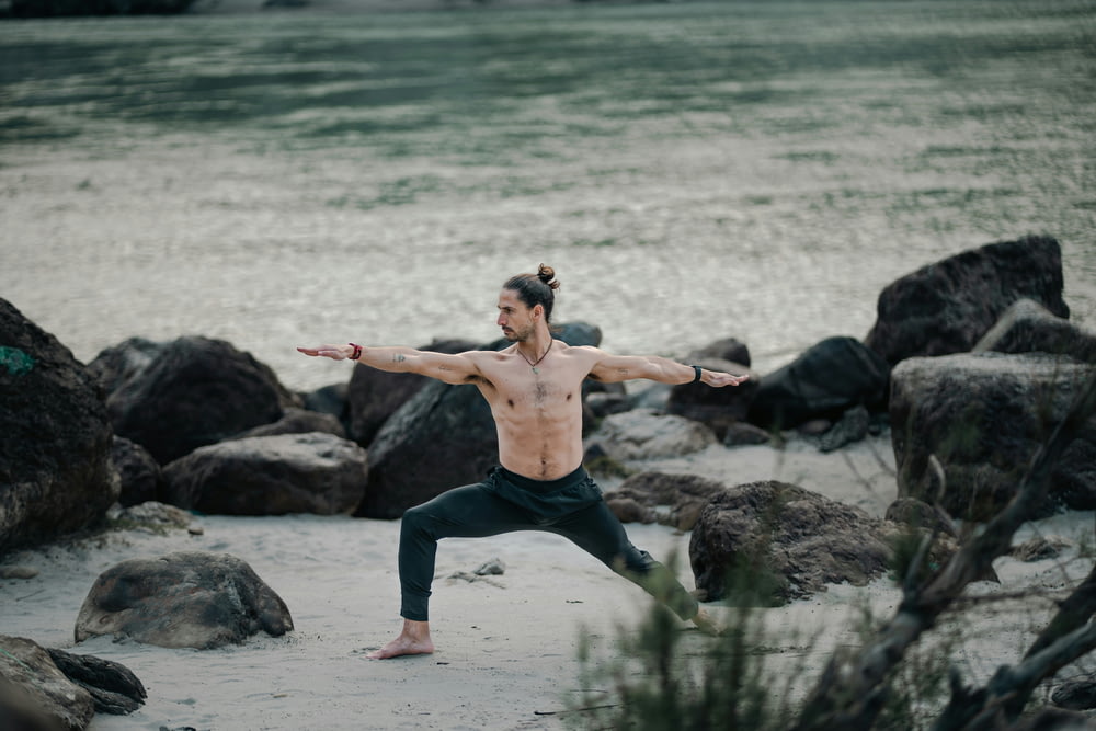 a man doing a yoga pose on the beach
