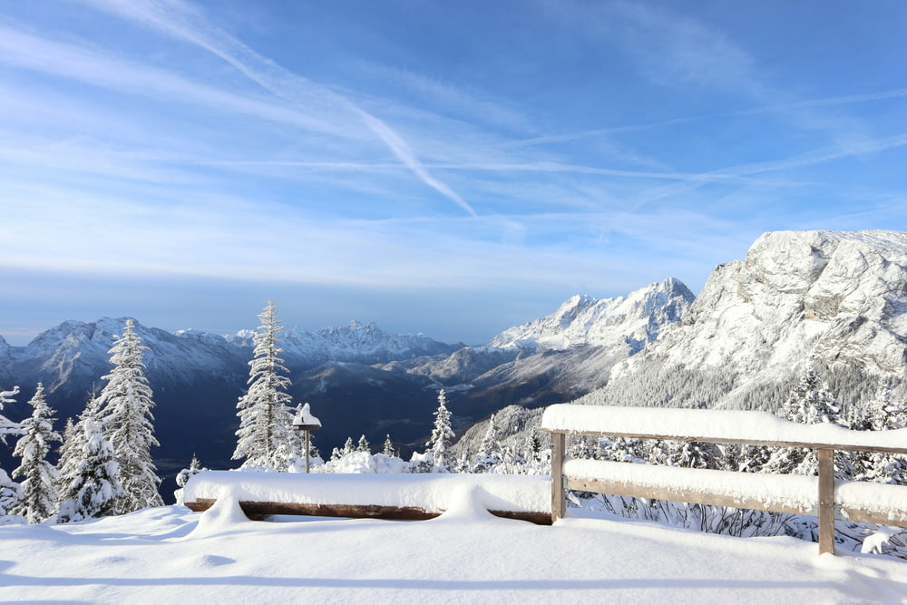 a bench on a snowy mountain overlooking the mountains