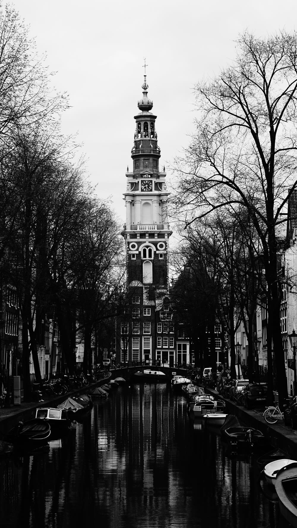 a black and white photo of a canal with a clock tower in the background