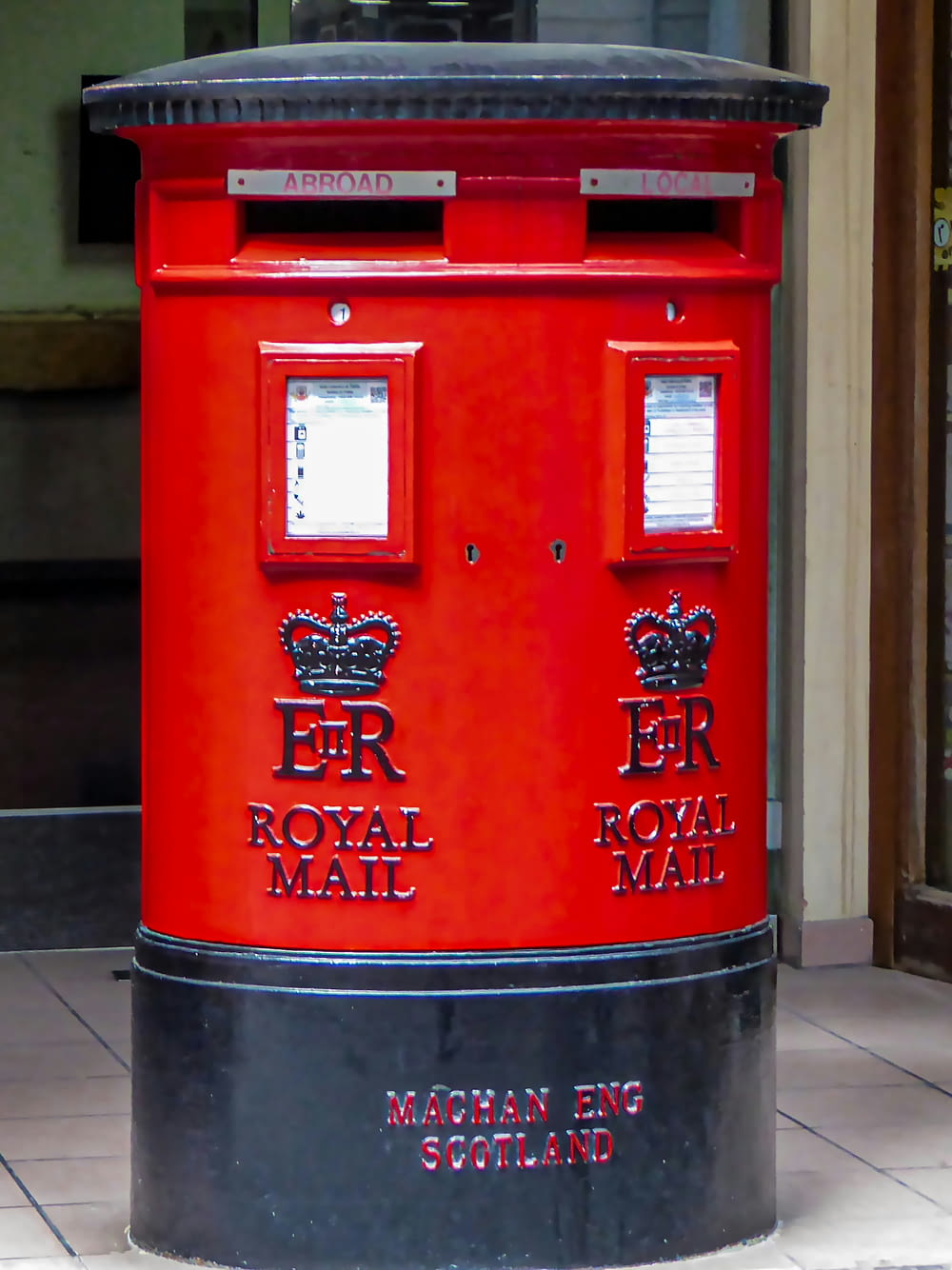 a red post box sitting on the side of a building