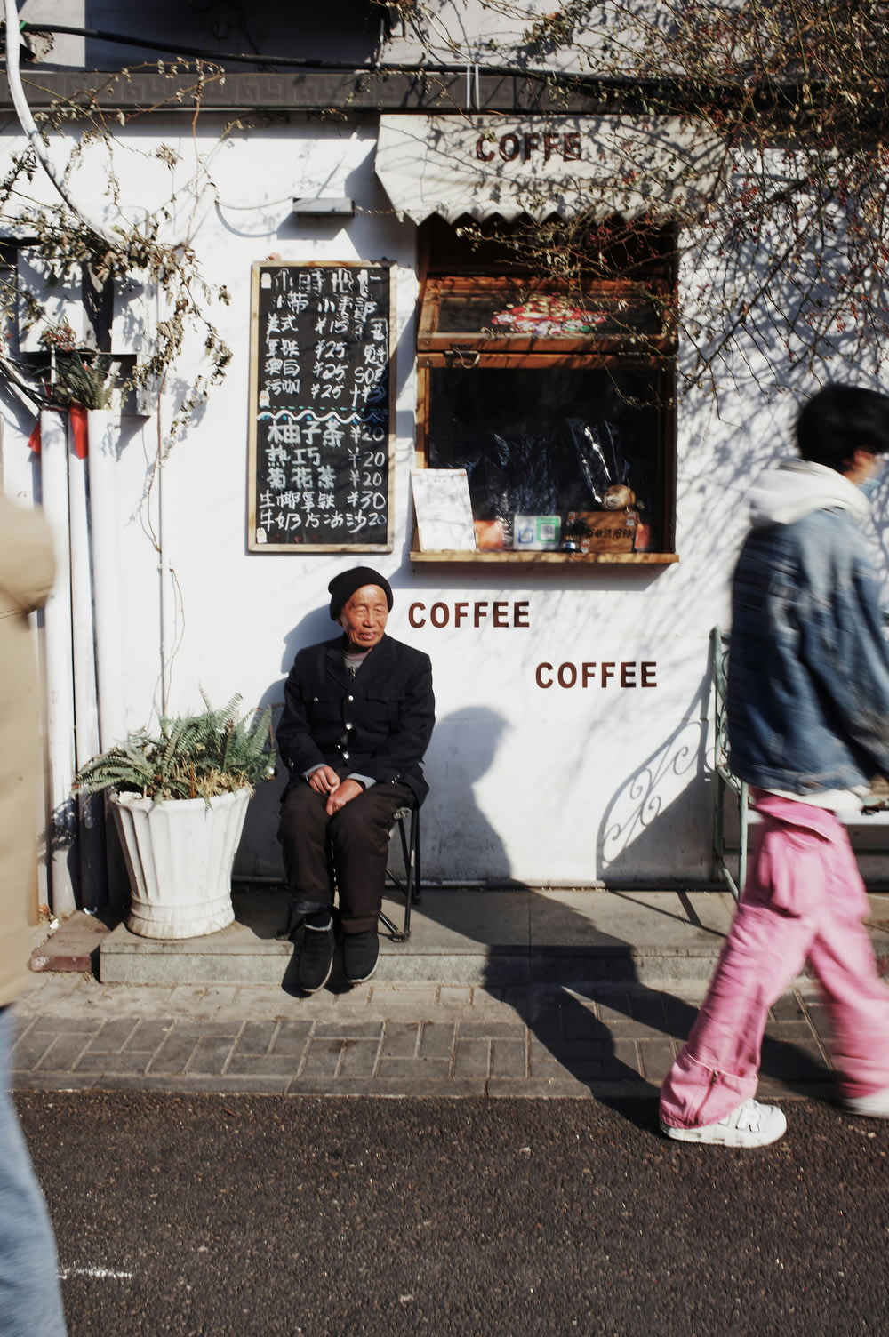 a man sitting on a bench in front of a coffee shop
