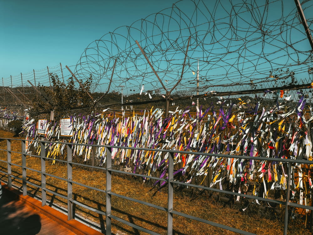 a fence covered in many different colored ribbons