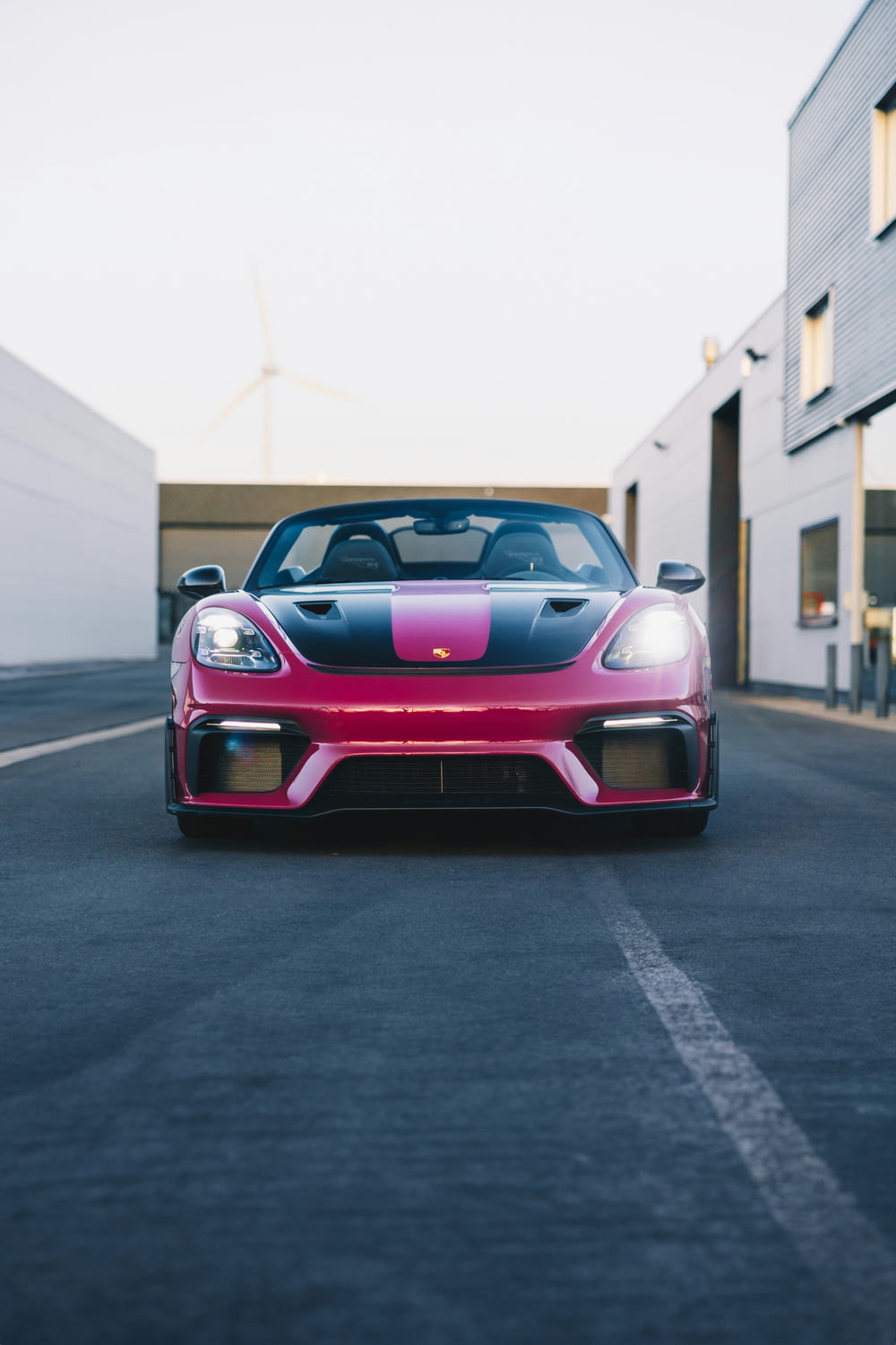 a pink and black sports car driving down a street