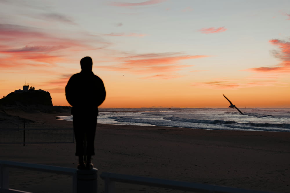 a man standing on a beach watching the sunset