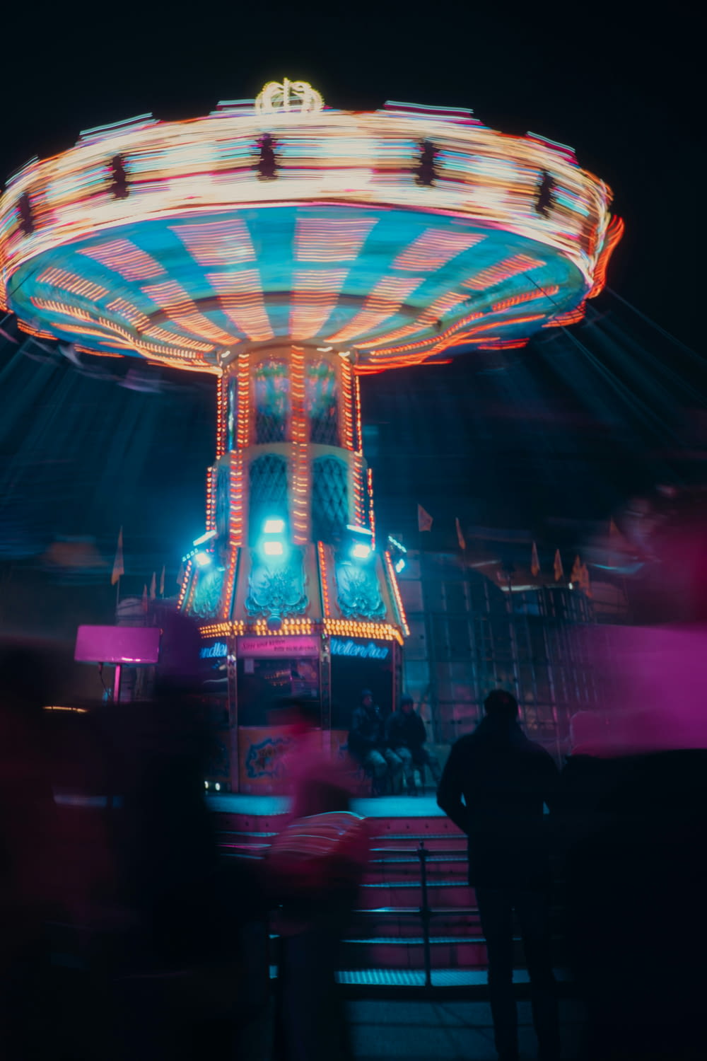 a carnival ride at night with people standing around