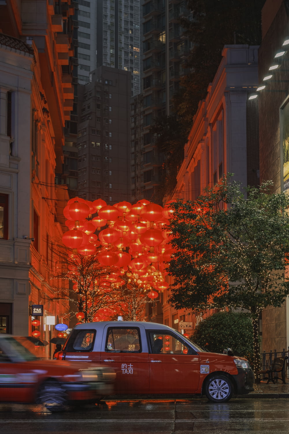 a red taxi driving down a street next to tall buildings