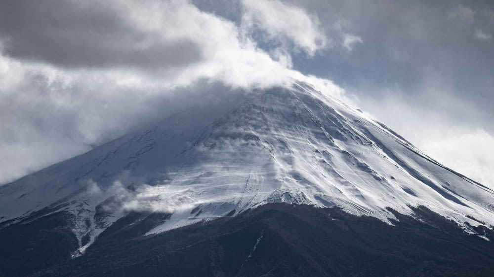 una grande montagna coperta di neve sotto un cielo nuvoloso