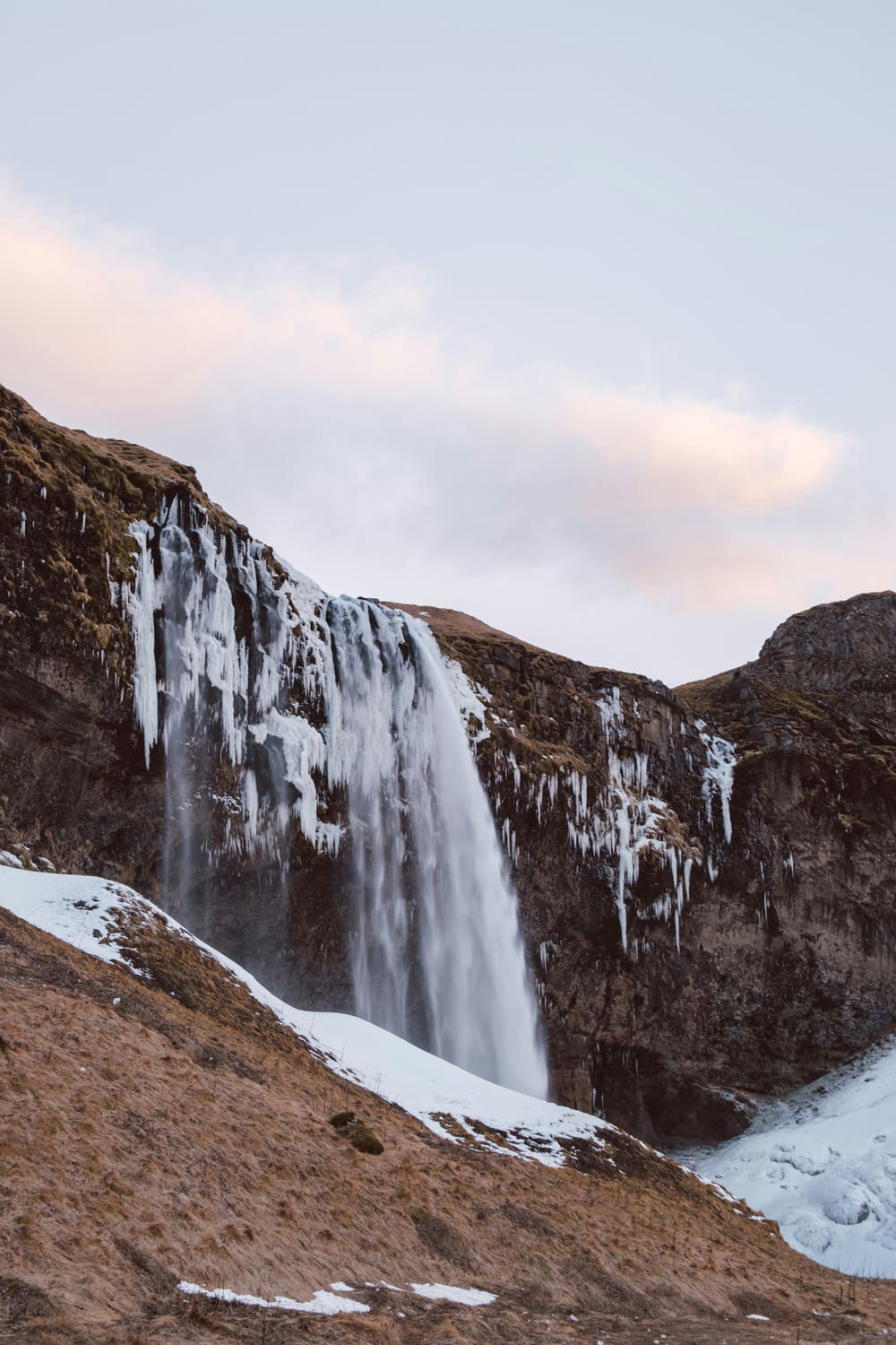 a very tall waterfall in the middle of a snowy field