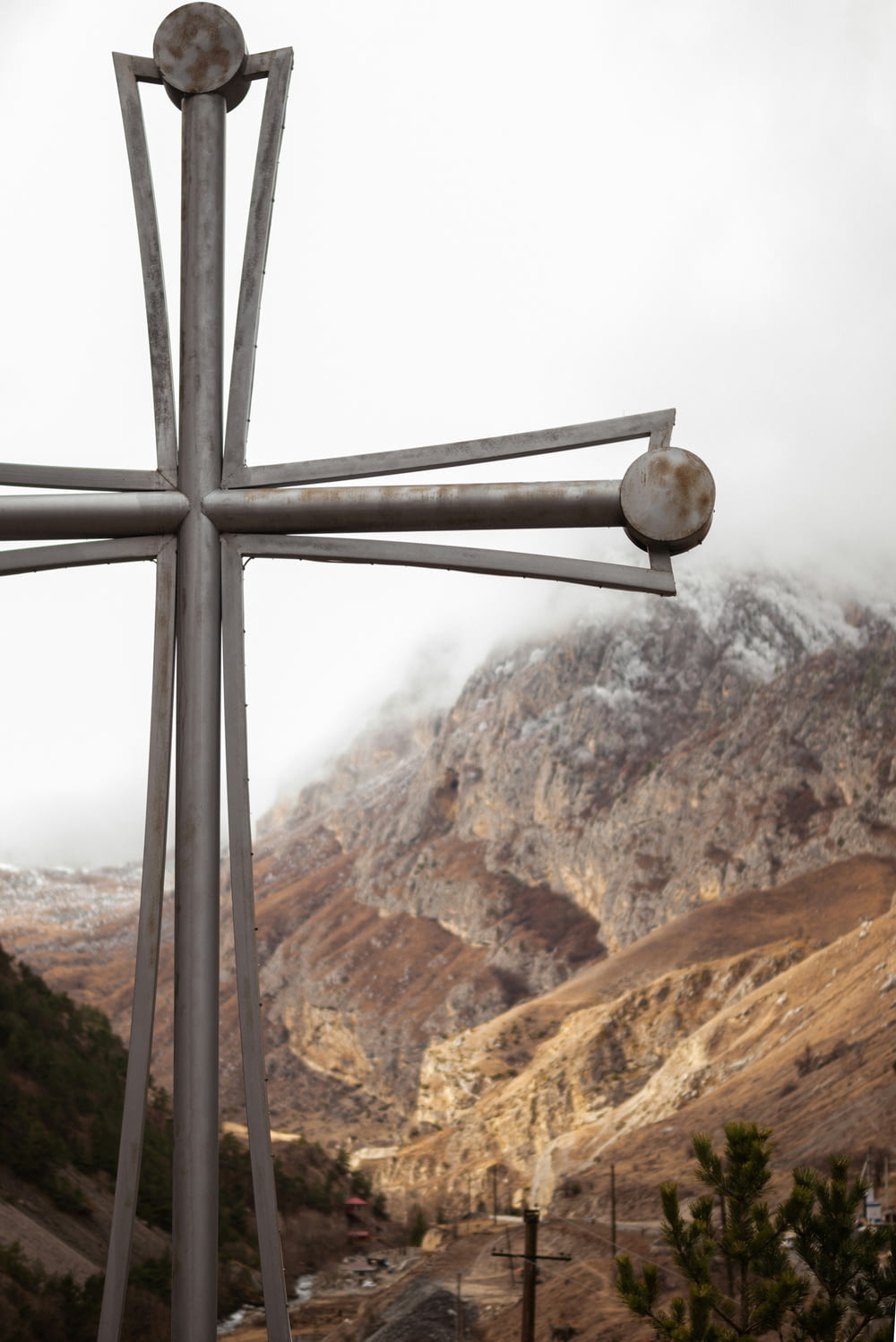 a large metal cross with a mountain in the background