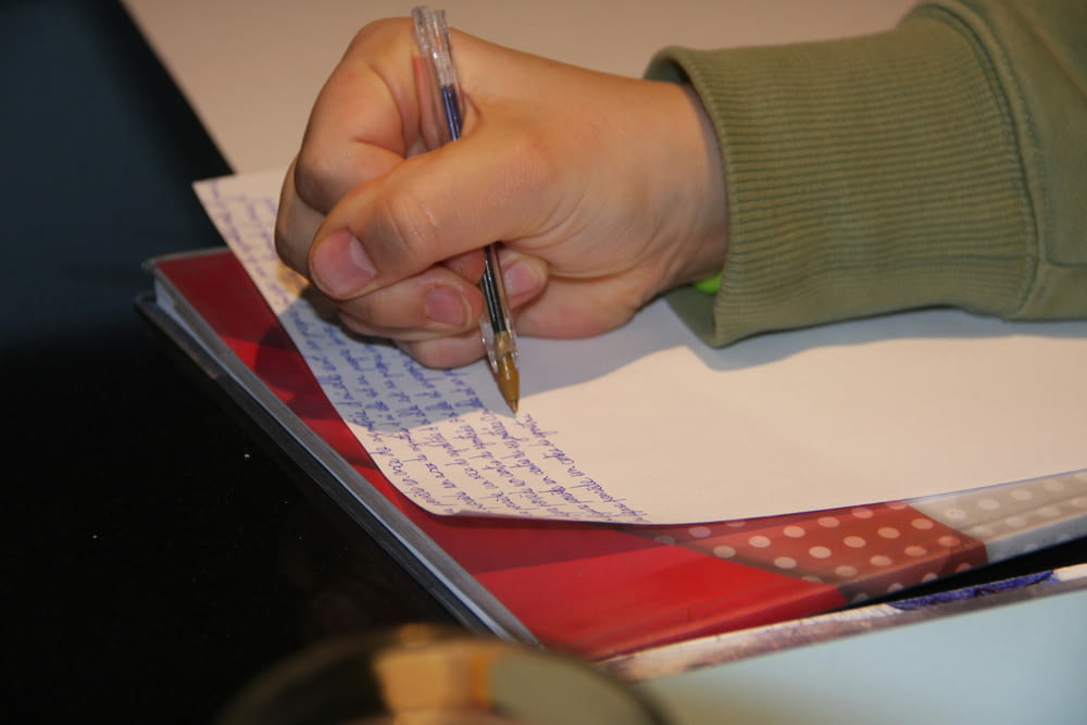 une personne écrivant sur une feuille de papier avec un stylo