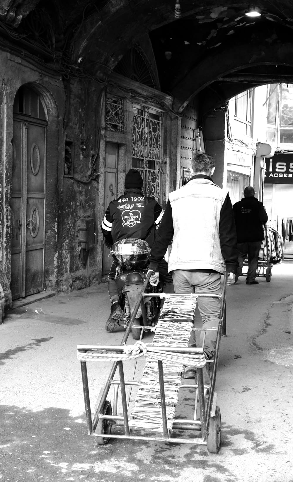 a black and white photo of a man pushing a cart