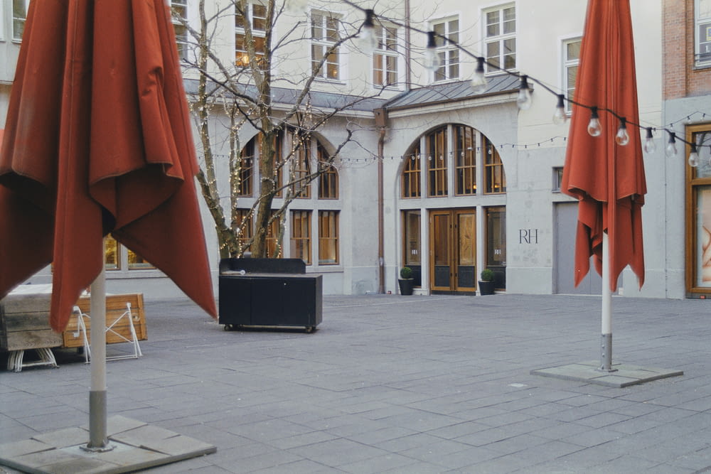 an empty courtyard with red umbrellas and chairs