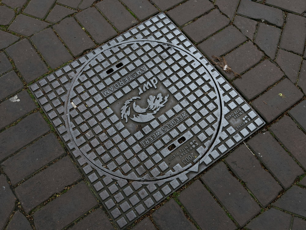 a manhole cover on a brick sidewalk