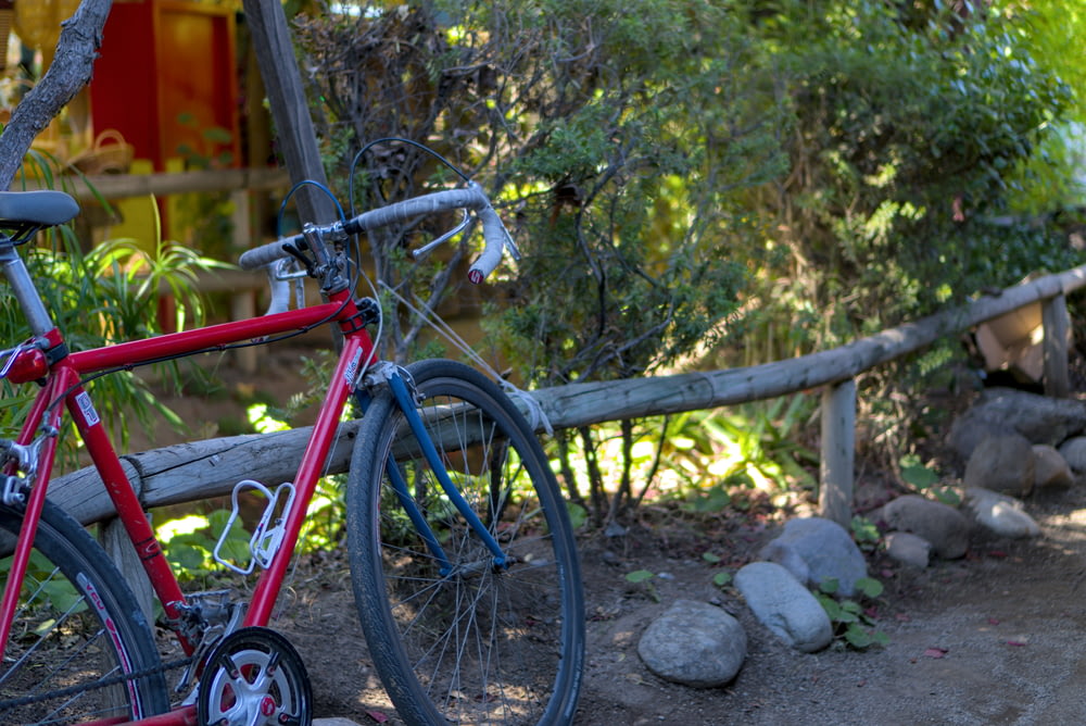 나무 울타리 옆에 주차된 빨간 자전거