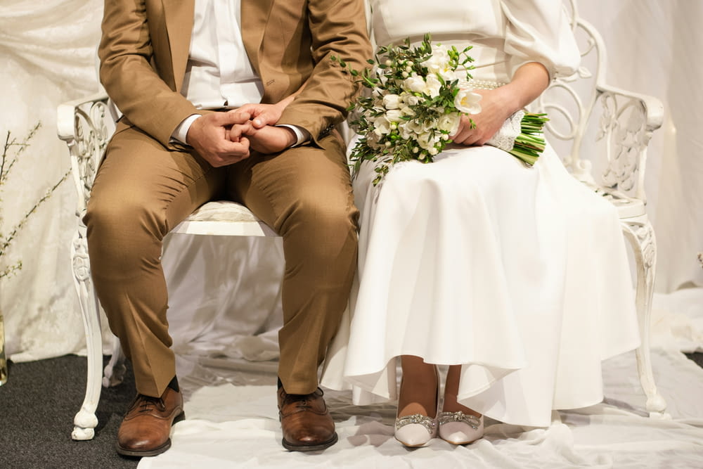 a bride and groom sitting on a white chair