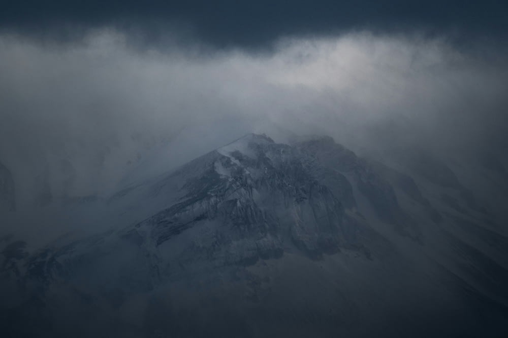 a large mountain covered in snow under a cloudy sky