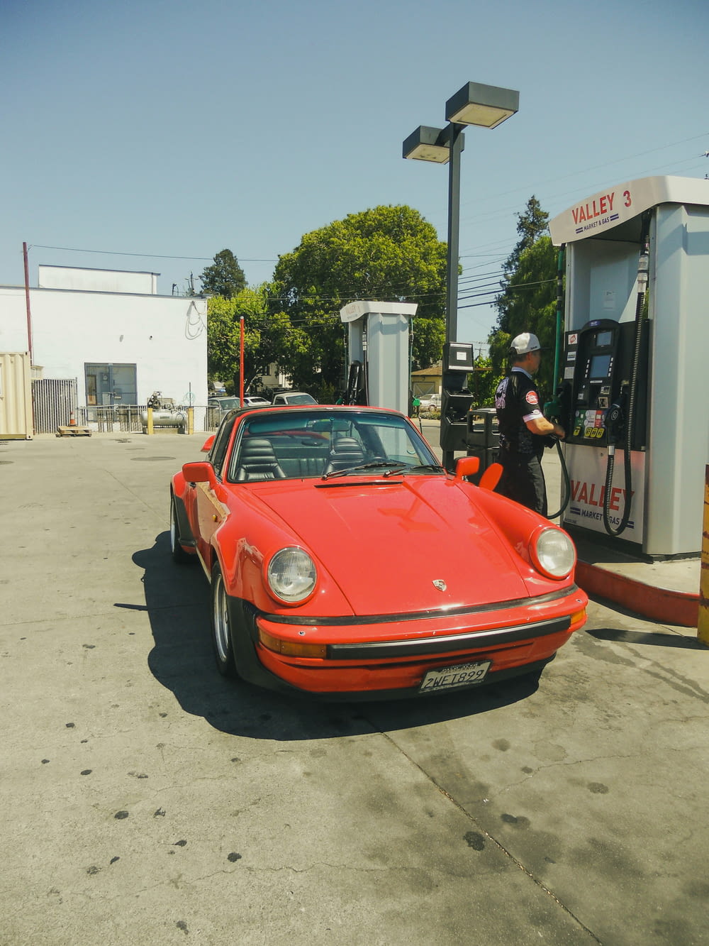 a red car parked next to a gas pump