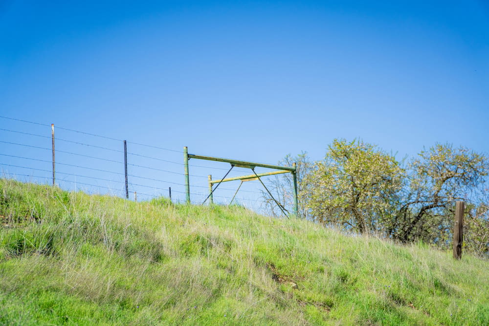 a grassy hill with a gate on top of it